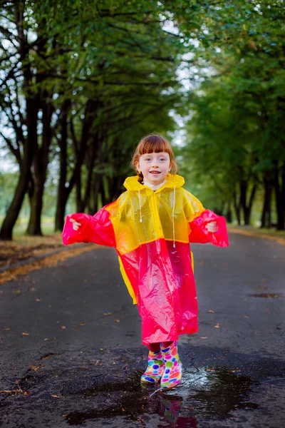 Little girl in rubber boots jumping in puddles