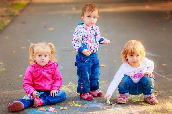 Children draw with crayons on the pavement