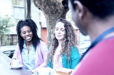 Kahve dükkanında iki güzel kadına kahve ve kek servisi yapan garson..