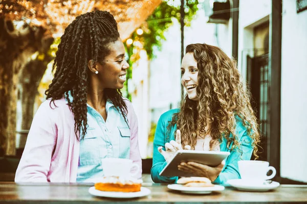 Two girlfriends watch the tablet at the Coffee Bakery shop.