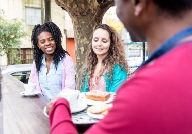 Siyah garson tarafından servis edilen iki genç kadın için kahve ve bisküvi..