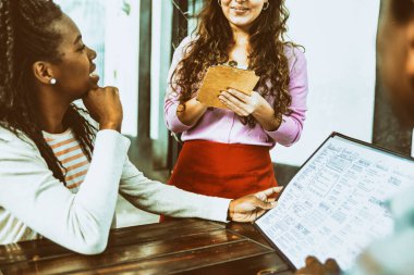 Afro-Amerikalı çift kahve dükkanındaki garsona sipariş veriyor..