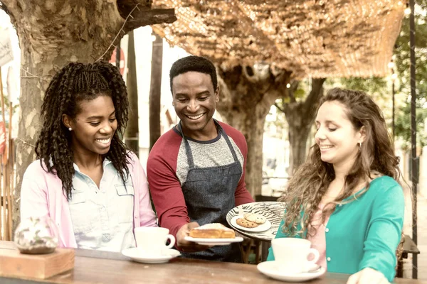 Young waiter serves two cute women.