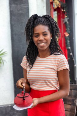 Genç Afrikalı Amerikalı garson çay için sıcak su tutuyor.