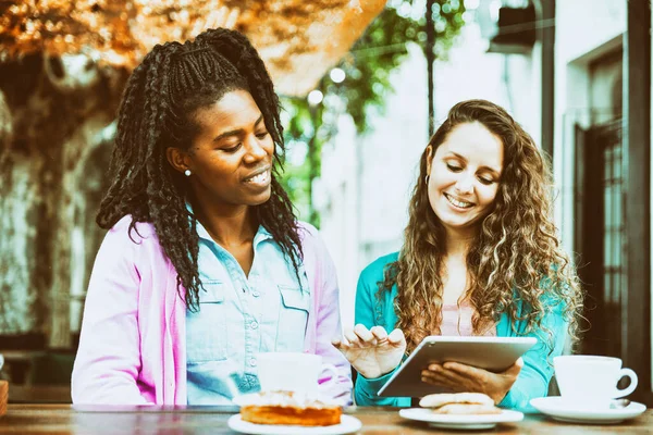 Two girls watch the tablet at the Coffee Bakery shop.