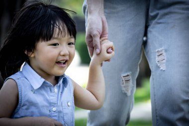 Parkta annesinin elini tutan Asyalı kız. Aile ilişkisi ve rahatlama zamanı kavramı.