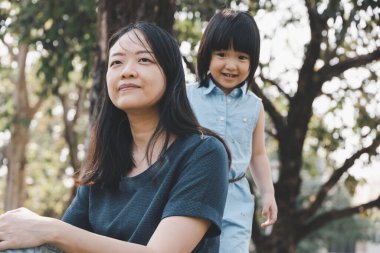 Asyalı küçük kızı ve annesi parkta. Aile ilişkisi ve rahatlama zamanı kavramı.