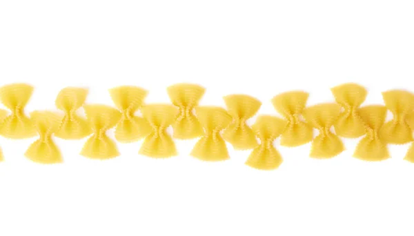 Lijn gemaakt van droge farfalle pasta over geïsoleerde witte achtergrond — Stockfoto