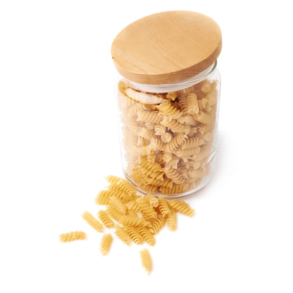 Glass jar filled with dry rotini pasta over isolated white background — Stock Photo, Image