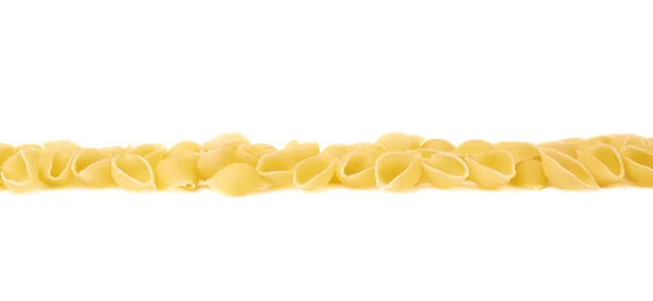 Line made of dry conchiglie pasta over isolated white background — Stock Photo, Image