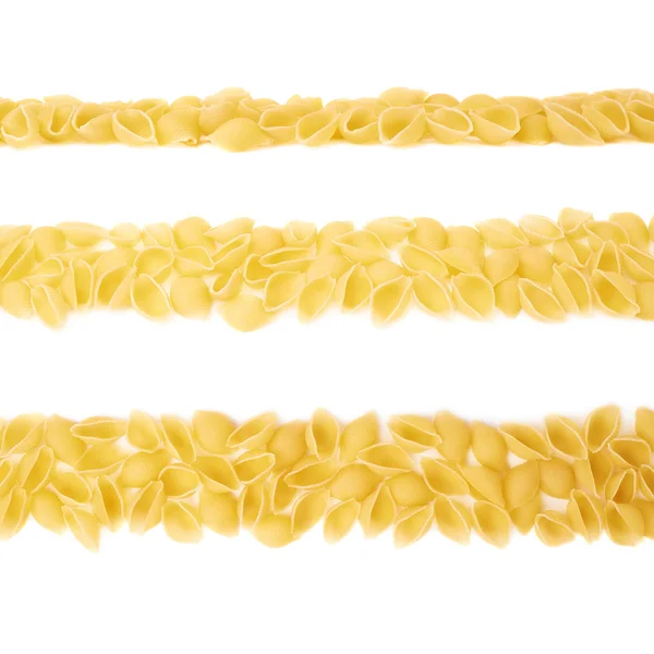 Linha feita de macarrão conchiglie seco sobre fundo branco isolado — Fotografia de Stock