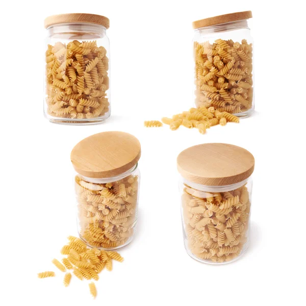 Set of glass jar filled with dry rotini pasta over isolated white background — Stock Photo, Image