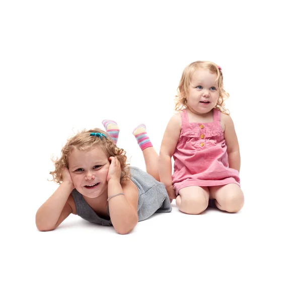 Couple of young little girls lying over isolated white background — Stock Photo, Image