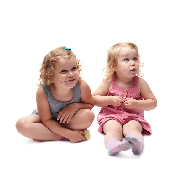 Couple of young little girl sitting over isolated white background — Stock Photo, Image