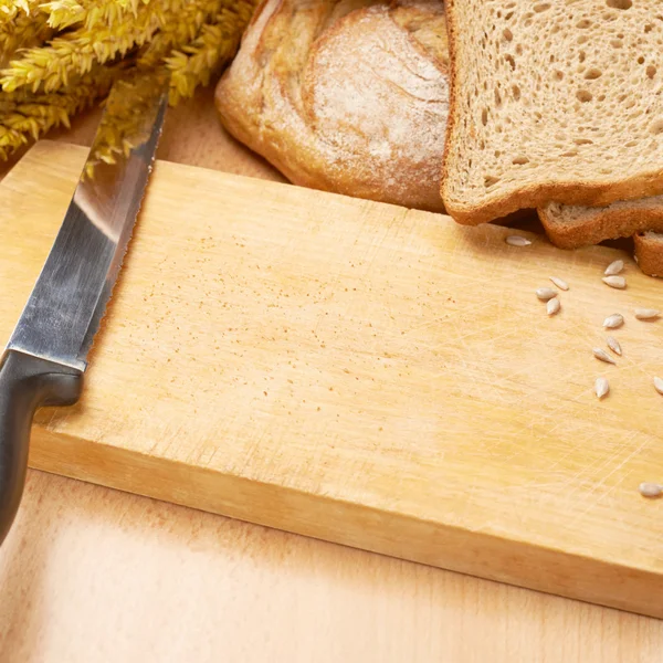 Bread and seeds over the cutting board — Stock Photo, Image