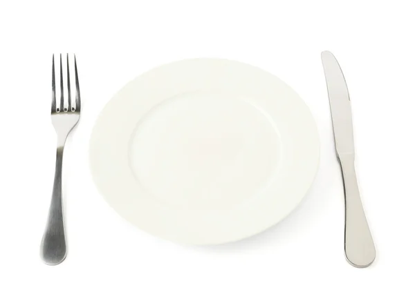 Fork and knife next to empty ceramic plate — Stock Photo, Image