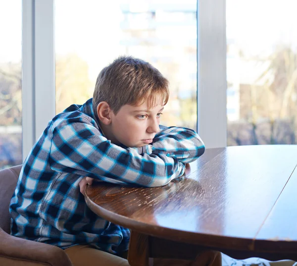 Boy sitting at the wooden desk — Stock Photo, Image