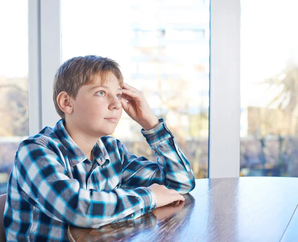 Junge sitzt am Holztisch — Stockfoto