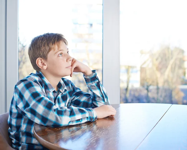 Junge sitzt am Holztisch — Stockfoto