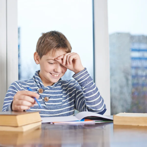 Boy sitting  over the pile of homework — Stock Photo, Image