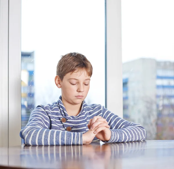 Pojken sitter medan be, — Stockfoto