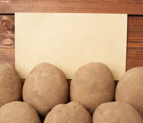Pile of potatoes against piece of paper — Stock Photo, Image
