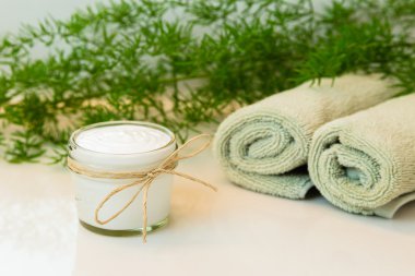 Cam mason kavanoza beyaz kremalı sicim yay ile dekore edilmiştir. Yeşil havlu bir spa ortamda haddelenmiş. Yeşil bitki dekor içinde geçmiş. Beyaz Banyo tezgah.
