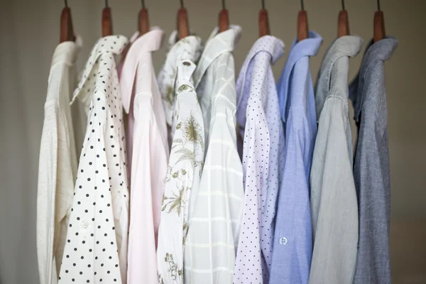 A row of assorted business shirts for women on hangers in a closet — Stock Photo, Image