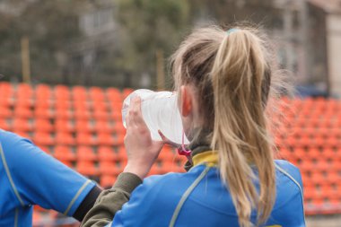 Sahadaki bayan sporcu şişeden su içer. Stadyumda kadın rugby oyuncusu