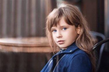 Küçük mavi gözlü kız kameraya bakıyor. İş elbiseli küçük kız..