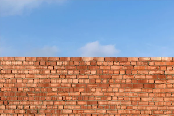 Brick flat wall on a background of blue sky. Brick wall on a construction site