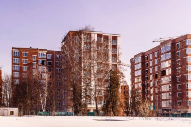 Ağaçlarla çevrili yeni yapılmış bir yerleşim yeri. Çok katlı binaları olan tamamlanmış bir inşaat alanı.