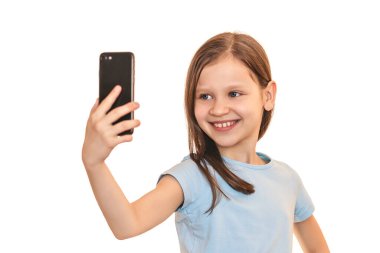 Gülümseyen kız beyaz bir arka planda selfie çekiyor. Elinde telefonla kameraya gülümseyen bir çocuk.