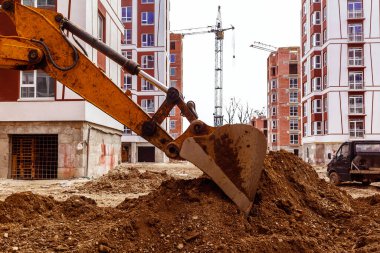 Sürüngen kazıcı bir inşaat alanında çalışıyor. Çok katlı binalarla iletişim kurmak.