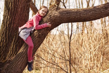 Küçük kız bir ağaca tırmandı ve büyük bir dala uzandı. Çocuk üzerinde yatan kocaman bir söğüt dalına sarıldı..