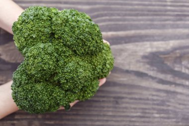 Ahşap zemin üzerinde yeşil brokoli. Kalp şeklinde brokoli kafası.