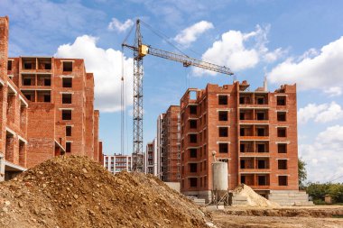 Kule vinci, çok katlı bina iskelesi ile döşenmiş. Tuğla evlerin arka planındaki inşaat sahasına kum yığını