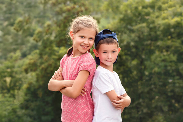 Мальчик и девочка стоят спиной друг к другу. Дети в природе на зеленом фоне