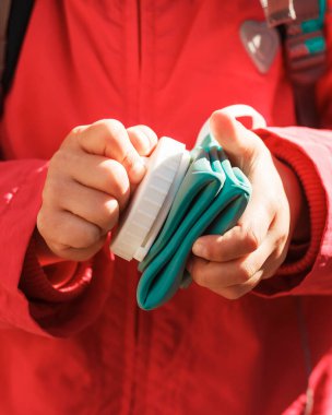 Kırmızı ceketli küçük bir kızın elinde katlanan silikon şişe.