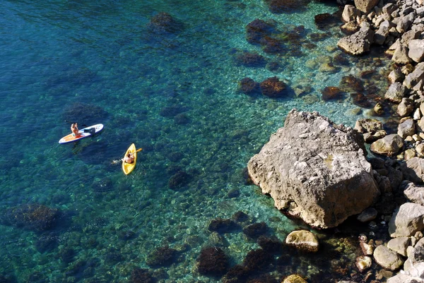 Turistler tarafından okyanusun kıyısında kayalık geçen bir kayık üzerinde