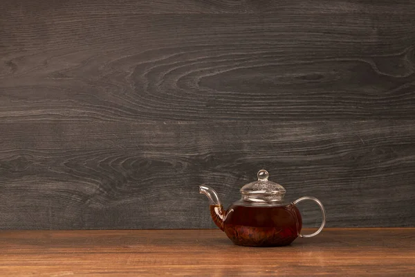 Glazen theepot met kopje zwarte thee op houten tafel. Kopieerruimte. — Stockfoto