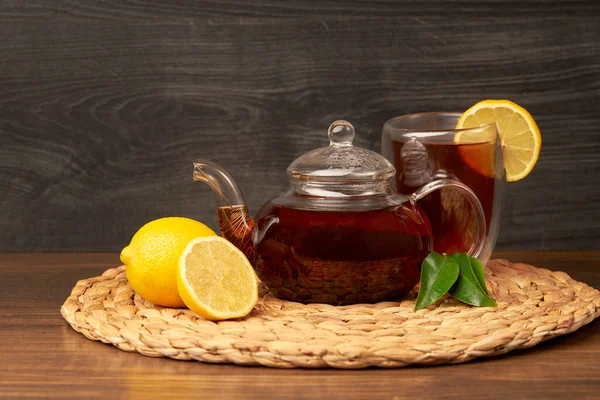 Cup of tea, glass teapot, lemon on a wooden table — Stock Photo, Image