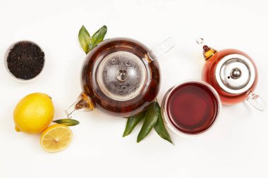 Çay konsepti, çaydanlık ve yeşil yapraklı bir fincan çay, limon, üst manzara.