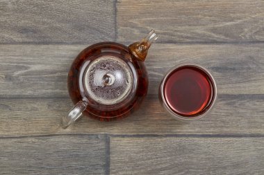 Bir bardak çaydanlık, bir fincan sıcak siyah çay ve ahşap bir masa. Üst görünüm