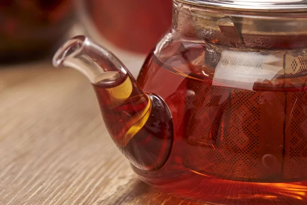 Close-up a hot tea in transparent glass teapot on the table with reflection. — Stock Photo, Image