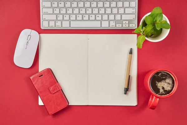 Rood bureau tafel met blanco notitieblok, toetsenbord en koffiebeker. Bovenaanzicht met kopieerruimte. — Stockfoto