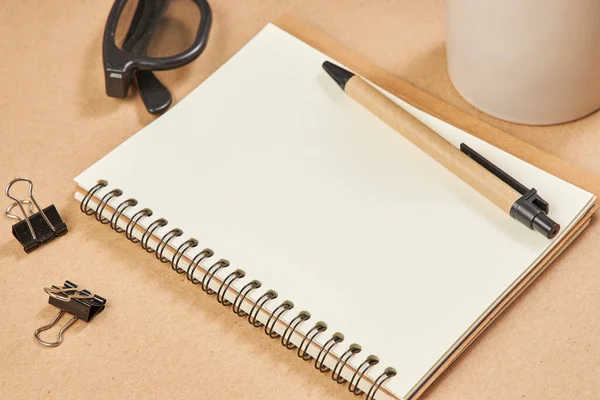 Vue du dessus d'une maquette de bureau : papier vierge et stylo, tasse à café sur fond beige — Photo