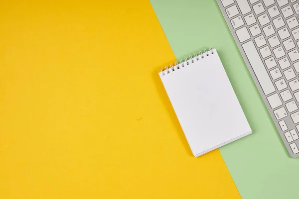 Geel en groen bureaublad. Bovenaanzichtstabel met notitieblok, toetsenbord. Mock up, kopieer ruimte. — Stockfoto
