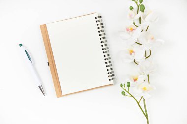 Boş not defteri, tahta masada kalem ve çiçek. Yukarıdan görüntüle