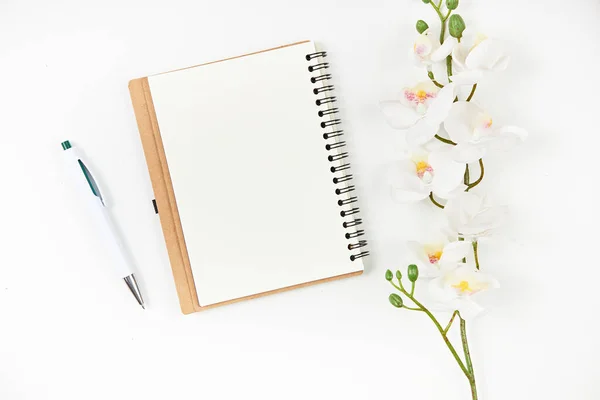 Blanco notitieblok, pen en bloem op houten tafel. Uitzicht van bovenaf Stockfoto